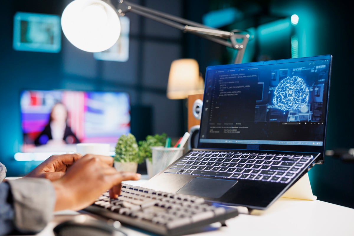 Profissional a trabalhar com laptop, usando tecnologia de IA e análise de dados em tempo real.