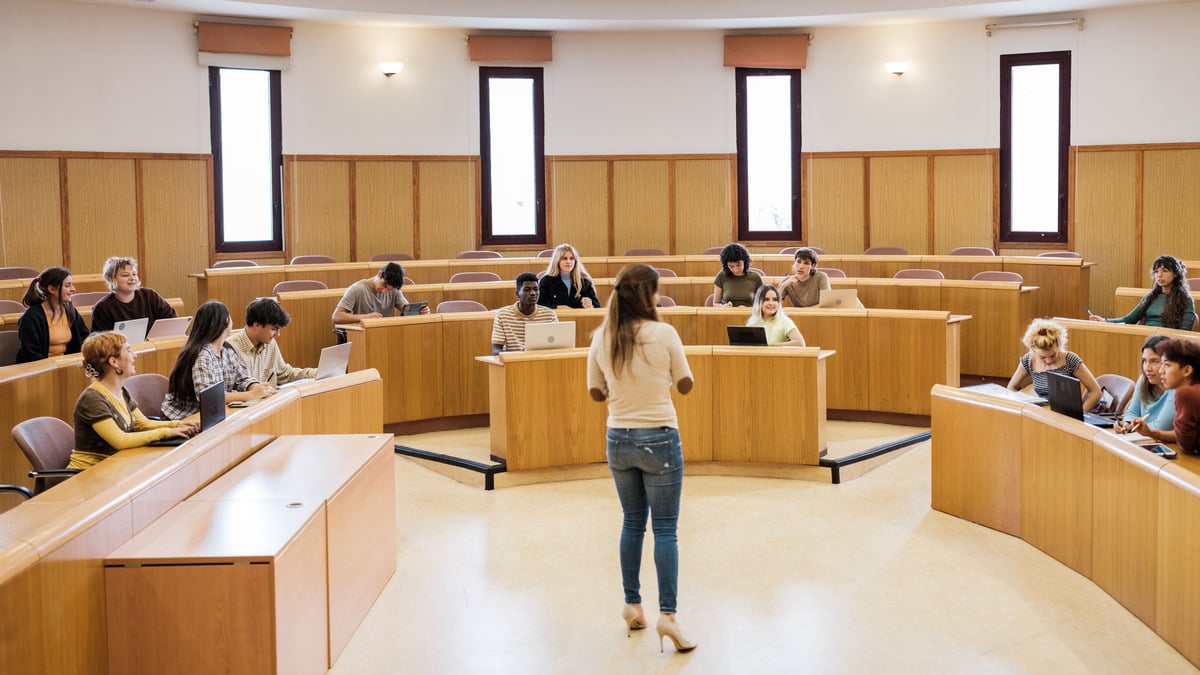 Sala de aula de MBA com alunos e professora, promovendo discussões estratégicas e de liderança.