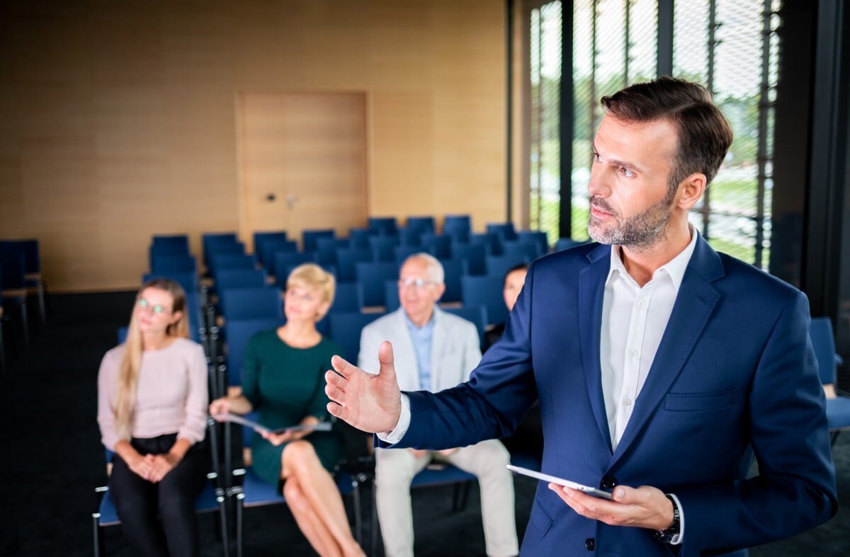 executivo apresenta modelo de estilos de liderança a grupo de gestores em auditorio