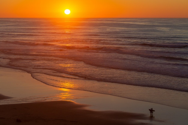 paisagem-de-um-belo-por-do-sol-refletindo-no-mar-da-praia-em-portugal-algarve_181624-7353