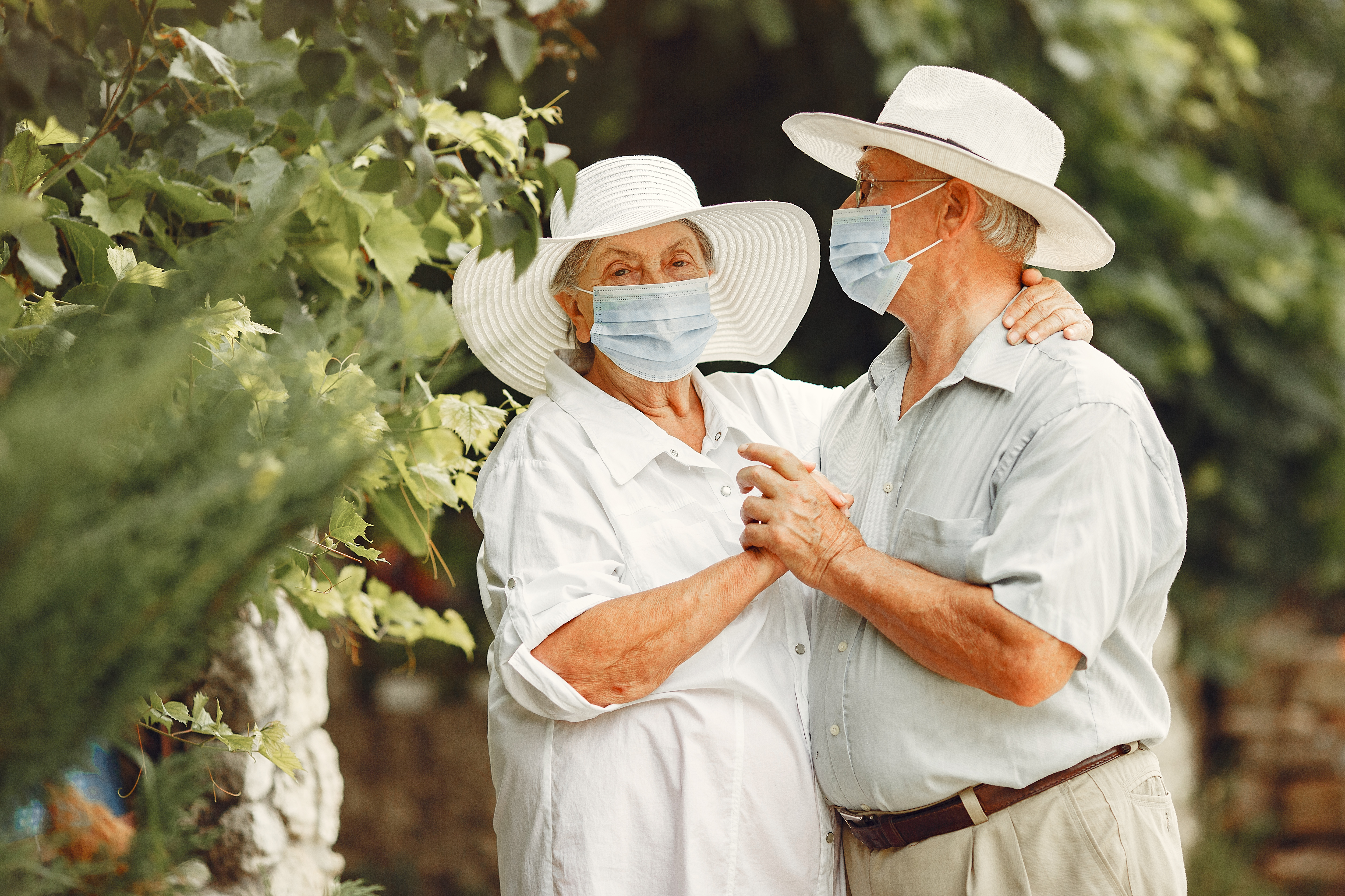 adult-couple-in-a-summer-garden-coromavirus-theme-people-in-a-medical-mask-handsome-senior-in-a-white-shirt